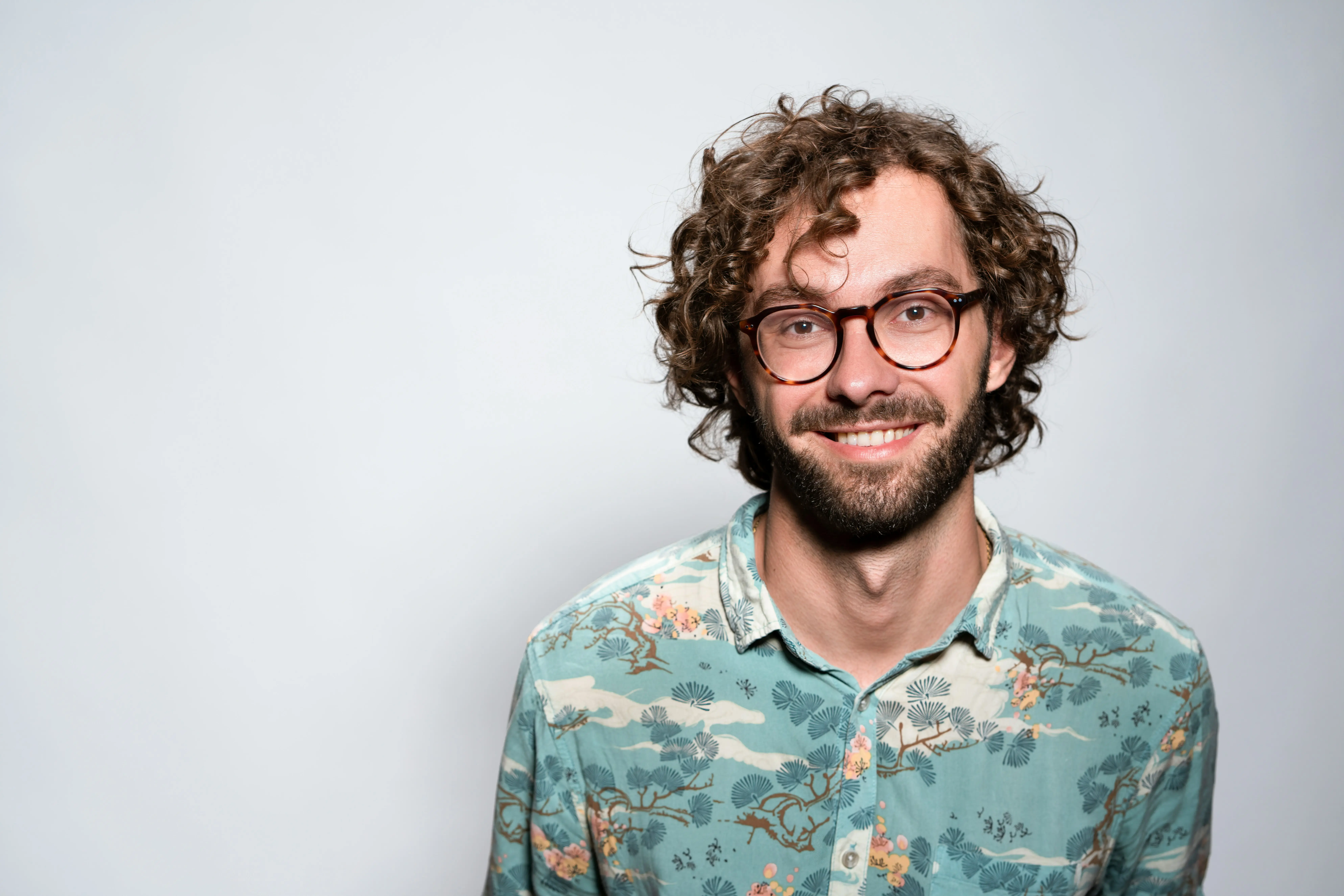 Thomas, 28 ans, apparait détendu. Il porte une chemise bleu à motif devant un fond gris. Il témoigne de son expérience d'un ton apaisé.